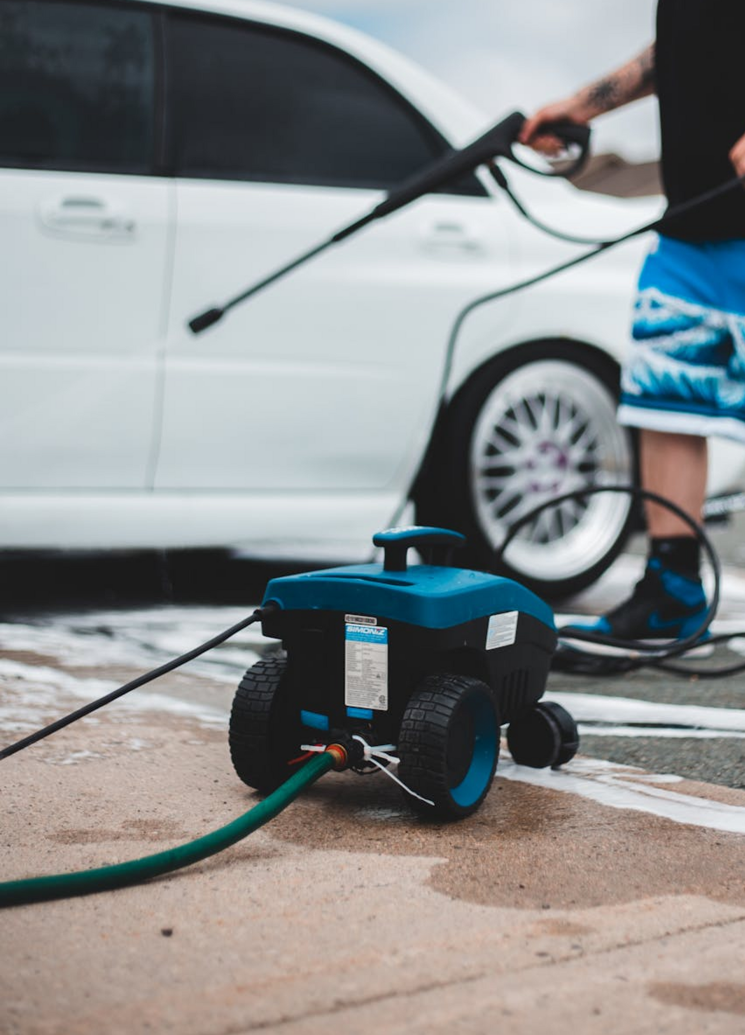 A man pressure washing a white car