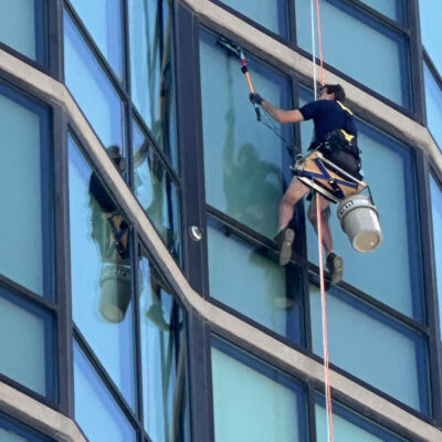 Window cleaner using rope access on a glass high rise in the Boise area