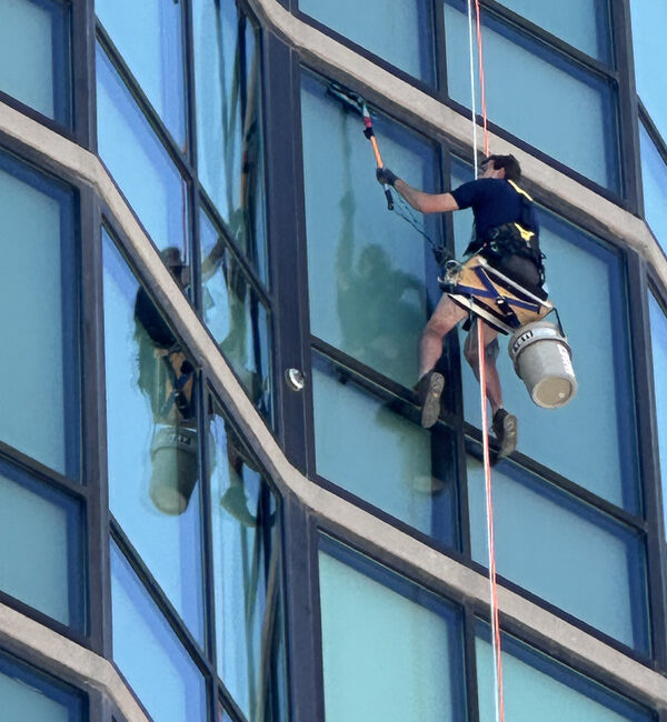 Window cleaner using rope access on a glass high rise in the Boise area