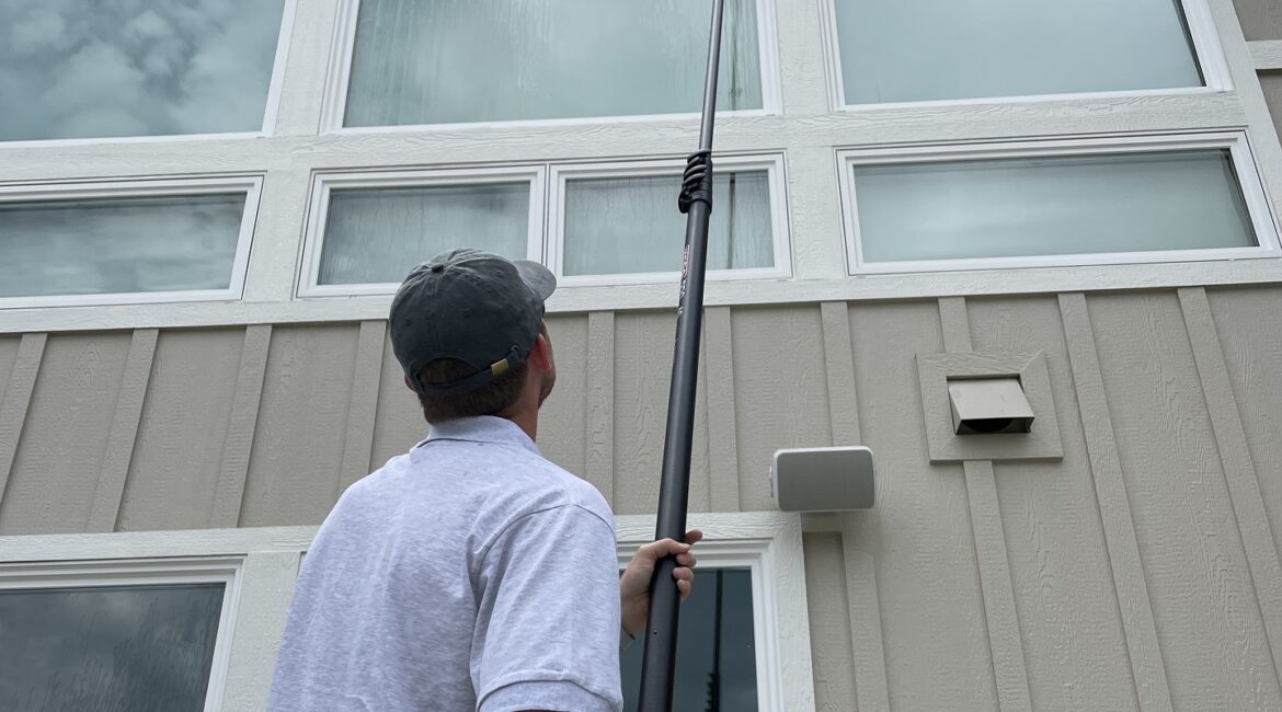 Technician cleaning home windows with a water fed pole in the Boise area
