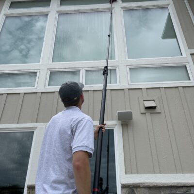 Technician cleaning home windows with a water fed pole in the Boise area